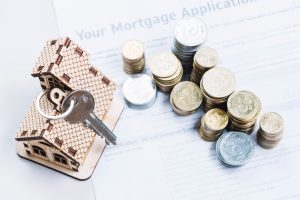 Illustrative image of a miniature house with coins next to it to talk about Mortgage Refinancing.